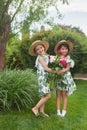 Portrait of smiling beautiful girls with bouquet of peonies against green grass at summer park.