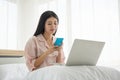 Portrait of smiling beautiful lady viewing mobile and working with notebook in morning on the bed with copy space Royalty Free Stock Photo