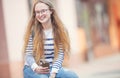 Portrait of a smiling beautiful teenage girl with dental braces. Young schoolgirl with school bag and mobile phone Royalty Free Stock Photo