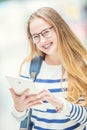 Portrait of a smiling beautiful teenage girl with dental braces. Young schoolgirl with school bag and tablet device Royalty Free Stock Photo