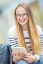 Portrait of a smiling beautiful teenage girl with dental braces. Young schoolgirl with school bag and tablet device Royalty Free Stock Photo