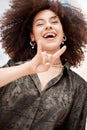 Portrait of smiling beautiful trendy mixed race woman with afro making cool hand gesture to pose alone outside. Below Royalty Free Stock Photo