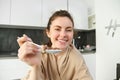 Portrait of smiling beautiful woman, feeding you spoon of cereals with milk, eating breakfast and looking happy Royalty Free Stock Photo