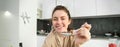 Portrait of smiling beautiful woman, feeding you spoon of cereals with milk, eating breakfast and looking happy Royalty Free Stock Photo