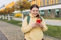 A portrait of a smiling beautiful woman texting sms with her phone on urban background. Happy student with backpack is Royalty Free Stock Photo