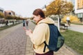 A portrait of a smiling beautiful woman texting sms with her phone on urban background. Happy student with backpack is Royalty Free Stock Photo