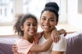 Portrait of smiling biracial mom and daughter cuddling at home Royalty Free Stock Photo
