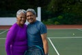 Portrait of smiling biracial senior couple embracing while standing in tennis court Royalty Free Stock Photo
