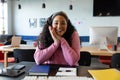 Portrait of smiling biracial young businesswoman sitting at desk in creative office Royalty Free Stock Photo