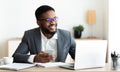 Portrait of smiling black businessman sitting at workplace with cellphone Royalty Free Stock Photo