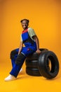 Portrait of smiling black female mechanic posing with new car tyres in studio Royalty Free Stock Photo