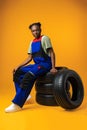 Portrait of smiling black female mechanic posing with new car tyres in studio Royalty Free Stock Photo