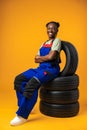 Portrait of smiling black female mechanic posing with new car tyres in studio Royalty Free Stock Photo