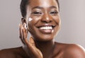 Portrait Of Smiling Black Woman Applying Moisturizing Cream on Face