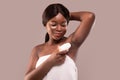 Portrait of smiling black woman applying roller deodorant to armpit zone Royalty Free Stock Photo