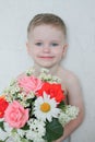 Portrait of smiling blond european cute boy with blue eyes on white background with a bouquet of flowers. Royalty Free Stock Photo