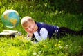 Portrait of smiling blond school boy discovering the globe russian on the grass