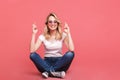 Portrait of smiling blond woman 20s wearing vintage sunglasses laughing while sitting on floor with legs crossed Royalty Free Stock Photo