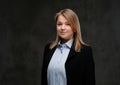 Portrait of a smiling blonde businesswoman formal dressed. Isolated on dark textured background.