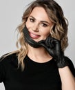 Portrait of smiling blonde curly woman in black t-shirt and latex gloves taking off her black protective medical mask