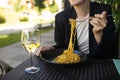 Portrait of a smiling blonde woman eating Italian pasta carbonara and wine at cozy italian restaurant outdoors. Royalty Free Stock Photo