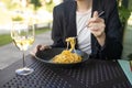 Portrait of a smiling blonde woman eating Italian pasta carbonara and wine at cozy italian restaurant outdoors. Royalty Free Stock Photo