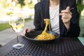 Portrait of a smiling blonde woman eating Italian pasta carbonara and wine at cozy italian restaurant outdoors. Royalty Free Stock Photo