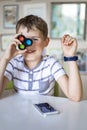 Portrait smiling boy fooling covering eye with simple dimple popit toy posing sitting at table Royalty Free Stock Photo