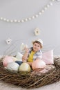 Portrait of a smiling boy in a hat. Easter composition with birds nest, easter eggs, dry willow branches. Royalty Free Stock Photo