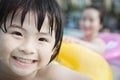 Portrait of smiling boy in the pool on a an inflatable tube with his mother in the background Royalty Free Stock Photo