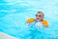 Portrait smiling boy in swimming pool, child in swimming glasses and inflatable sleeves. Summer travel hotel vacation or Royalty Free Stock Photo