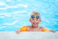 Portrait smiling boy in swimming pool, child in swimming glasses and inflatable sleeves. Summer travel hotel vacation or Royalty Free Stock Photo