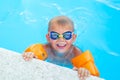 Portrait smiling boy in swimming pool, child in swimming glasses and inflatable sleeves. Summer travel hotel vacation or Royalty Free Stock Photo