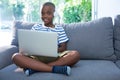 Portrait of smiling boy using laptop while listening to headphones at home Royalty Free Stock Photo