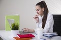 Portrait of a smiling brown haired businesswoman in a white blouse sitting at her table in an office. Royalty Free Stock Photo