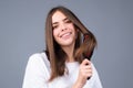 Portrait of smiling brunette hair lady combing hair with hairbrush comb, isolated. Young beautiful woman brush long Royalty Free Stock Photo