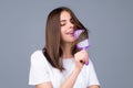 Portrait of smiling brunette hair lady combing hair with hairbrush comb, isolated. Young beautiful woman brush long Royalty Free Stock Photo