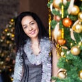 Portrait of smiling brunette woman near decotated Christmas tree