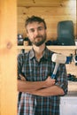 Portrait of smiling brutal bearded worker man stands in workshop with mallet, construction carpentry tools in the background. DIY