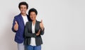 Portrait of smiling business colleagues showing thumbs up signs while standing on white background Royalty Free Stock Photo