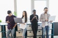 Portrait of smiling business colleagues using mobile phone and laptop in office Royalty Free Stock Photo