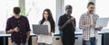 Portrait of smiling business colleagues using mobile phone and laptop in office Royalty Free Stock Photo