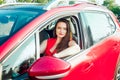 Portrait of smiling business lady, caucasian young woman driver in red clothes looking at camera and smiling while sitting behind Royalty Free Stock Photo