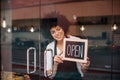 Smiling business woman putting an open sign on the glass door Royalty Free Stock Photo
