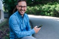 Portrait of cheerful businessman using smart phone while sitting by the road Royalty Free Stock Photo