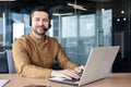 Portrait of a smiling businessman wearing a headset working in the office at a laptop. Sitting at the table and looking Royalty Free Stock Photo