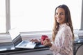 Portrait of smiling businesswoman holding coffee cup while working on laptop Royalty Free Stock Photo