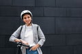 Portrait of a smiling businesswoman leaning on handlebar of electric push scooter. Young cheerful female in cycling helmet at