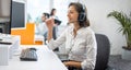 Portrait of smiling businesswoman listening to client via headset and answering customer calls in call center office Royalty Free Stock Photo