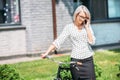 portrait of smiling businesswoman with retro bicycle talking on smartphone